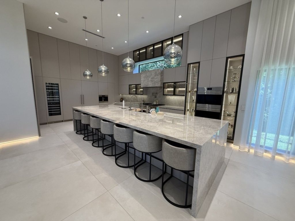 Custom kitchen with a long marble island and glass display cabinets