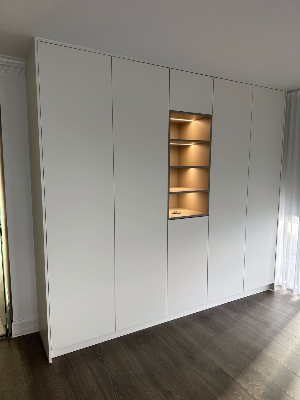 White built-in wardrobe with a lit niche
