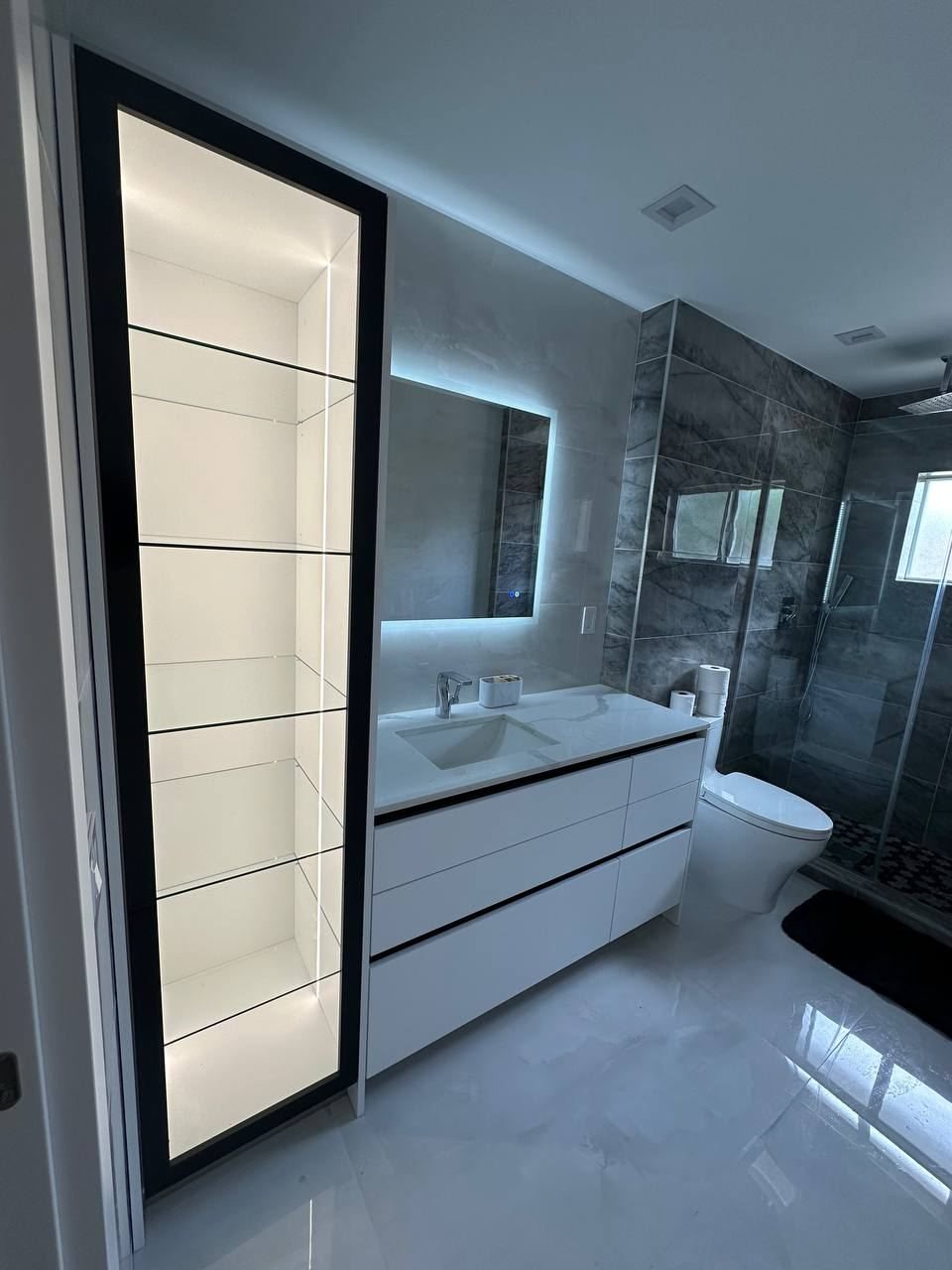 Bathroom vanity with a lit glass cabinet